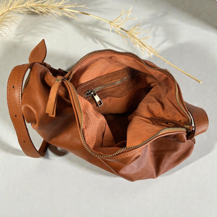 Brown full grain leather bag with a zipper on a light background. Internal view