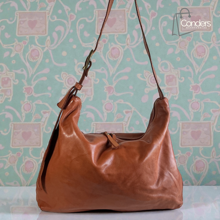 Brown leather handbag on a light blue background with floral and heart patterns