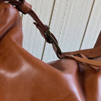 Close-up of a brown leather handbag with a wooden background