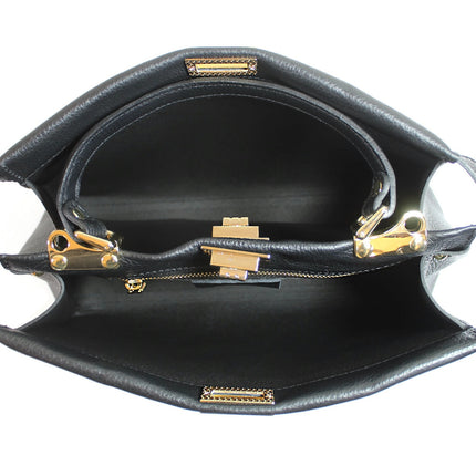 Black handbag with gold tone fittings on a white background. Internal view.