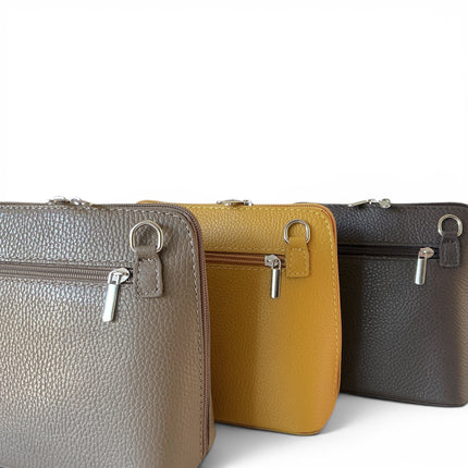 Three pebbled leather zip-around crossbody bags in dark taupe, mustard and dark brown, arranged in a row against a white background.