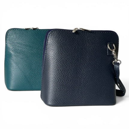 Two textured leather zip-around crossbody bags on a white background, one in teal and one in navy blue, both with silver-tone hardware and adjustable strap.