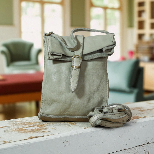 Mint leather bag with strap on a wooden surface in a room with furniture.