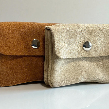 Two small suede leather pouches, one brown and one beige, with silver buttons on a light gray background.